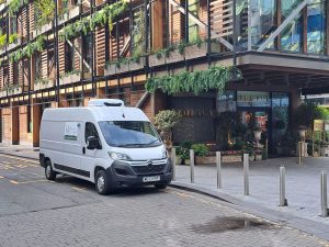 Courier delivering a parcel swiftly in an urban setting, with the cityscape in the background